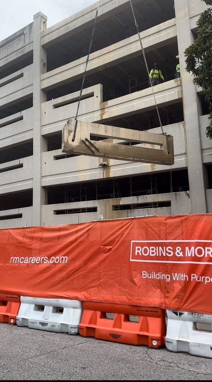concrete slab being hoisted up on parking garage construction site